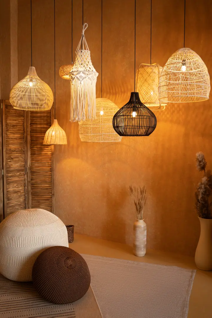 Un angolo dello showroom la sera: lampade di vimini e di macramè accese sopra due pouf di maglia